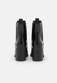 Black patent leather ankle boots with a square toe and chunky block heel. Features a logo at the back and elastic side panels for easy wear.