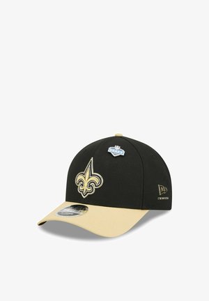 Czarna i beżowa czapka New Era z logo fleur-de-lis z przodu, odznaką NFL Draft na górze oraz logo New Era po boku.