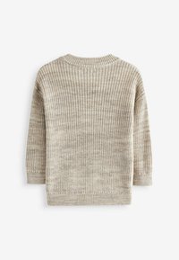 Beige stickad tröja med en texturerad tyg, sänkt axlar och ribbade manschetter och nederkant. Har långa ärmar och rund halsringning.
