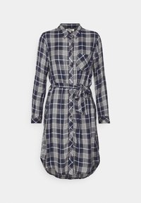 Robe chemise à manches longues à carreaux bleu marine et blanc, avec patte de boutonnage sur le devant, poche poitrine, col et ceinture en tissu nouée à la taille.