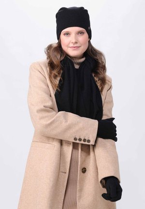 Knit black beanie, black scarf, and gloves paired with a light beige coat and brown turtleneck. Smooth textures and simple design.