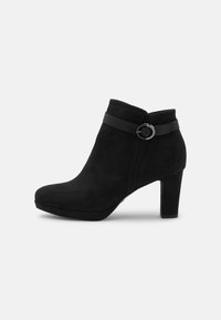 Mustat mokkanahkasaappaat, joissa on pyöristetty kärki, sivuvetoketju ja koristeellinen hihna, jossa on pyöreä solki. Keskikorkeat tukevat korot.