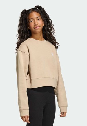 Cropped beige sweatshirt with long sleeves, round neckline, and white logo detail. Paired with black leggings. Smooth texture.
