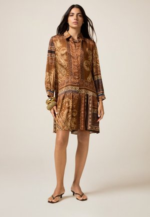 Abito marrone a fantasia con maniche lunghe, chiusura a bottoni e gonna svasata. Presenta design paisley e geometrici, completati da un bracciale testurizzato.