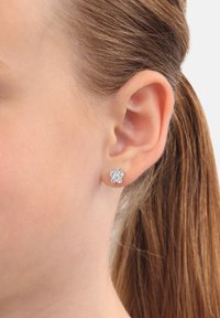Pendientes de stud en forma de mariposa de plata, con múltiples acentos de cristal brillante, colocados sobre piel suave en una vista de cerca.