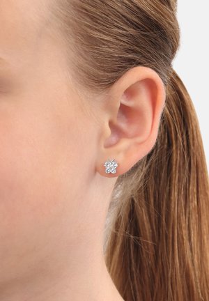 Orecchini a perno a forma di farfalla in argento, con numerosi accenti di cristallo scintillante, su una pelle liscia in primo piano.