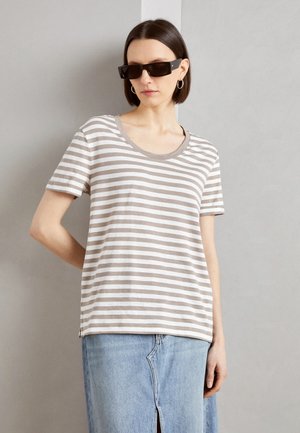 T-shirt rayé beige et blanc, avec un col rond et des manches courtes, associé à une jupe en denim. Tissu en coton texturé.