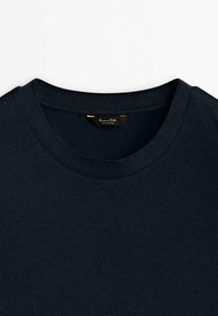 Pull bleu marine à col rond avec un col côtelé et une étiquette noire visible à l'intérieur du col portant l'inscription "Massimo Dutti".