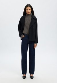 Czarny płaszcz typu pea coat z mieszanki wełny z podwójnymi guzikami, noszony na szarym swetrze z golfem, w połączeniu z ciemnymi dżinsami o prostych nogawkach i czarnymi balerinami.