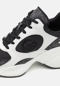 Baskets noir et blanc en cuir texturé et mesh. Elles présentent un bout arrondi, une semelle épaisse en caoutchouc et un logo embossé sur le côté.