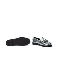 Mocasines metálicos plateados con acento de hebilla, parte superior de cuero y suela de goma negra, que exhiben un diseño clásico y una textura suave.