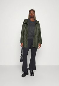 Green faux leather jacket with a hood, paired with a gray sweater, black pants, and chunky black boots; discreet handbag included.