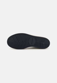 Semelle de chaussure en caoutchouc présentant un motif en zigzag noir, avec des détails de marque embossés et un bord lisse pour la durabilité et l'adhérence.