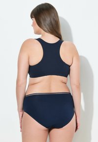 Sada navy modré podprsenky a vysokých kalhotek. Vyrobena z hladkého materiálu s vroubkovaným výstřihem a jemným elastickým páskem na kalhotkách.