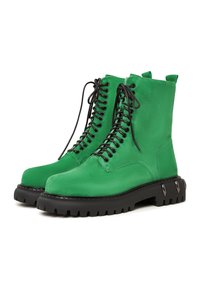 Groene suède enkellaarzen met zwarte veters, dikke rubberen loopzool en metalen accentdetails aan de zijkant. Rechte ontwerp met een gewatteerde kraag.