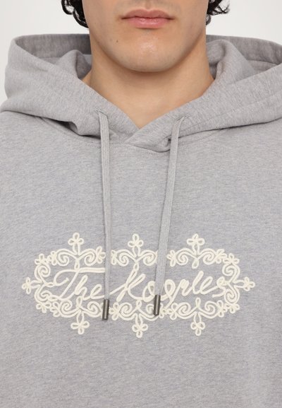 Grau Hoodie mit einer Kordel, das eine weiße verzierte Stickerei aufweist, die "Die Menschen" auf der Brust zentriert liest. Weicher Stoff und lässiges Design.