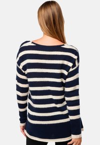 Pull rayé marine et crème avec une coupe décontractée, un large col et de longues manches, fabriqué dans un tissu tricoté doux et texturé.