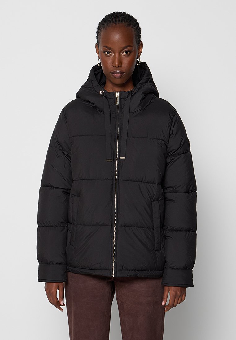 Chaqueta de plumas negra con capucha, con cierre de cremallera en la parte delantera, cordones elásticos y textura acolchada. Material suave con un corte holgado.