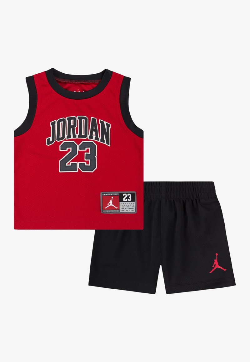 Sarkans tīkls sporta krekls ar uzrakstu "JORDAN 23" melniem treknraksta burtiem, kombineēts ar melnām šortām ar sarkanu Jumpman logotipu. Viegls sporta apģērbs.