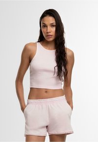Lichtroze cropped tanktop met een geribbelde textuur, gecombineerd met bijpassende zachte shorts met een elastische tailleband en zijzakken.