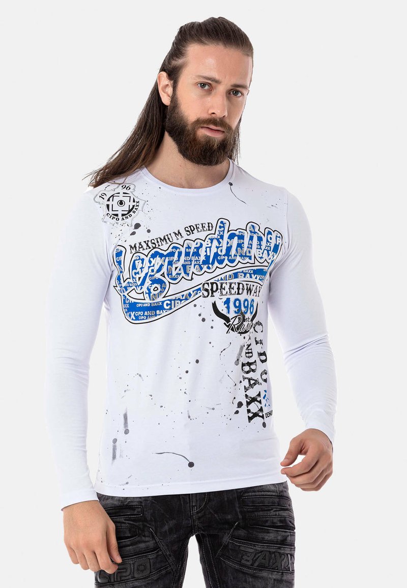 Weißes Langarmhemd mit blauen Grafiken und schwarzem Text, das mit Farbeffekten gestaltet ist. Passt gut zu dunklen Jeans.