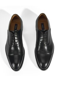 Chaussures habillées en cuir noir avec un bout rond, des coutures décoratives et un design profil bas avec une finition lisse.