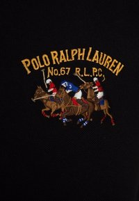 Broderie de trois joueurs de polo à cheval avec des maillets, portant des uniformes rouges, bleus et blancs, sous le texte jaune "Polo Ralph Lauren No.67 R.L.P.C."