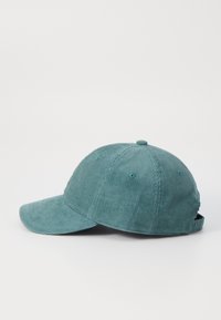 Teal kordfløyels baseball cap med buet skygge, teksturert stoff, justerbar stropp bak, og seks ventilasjonsøyler.