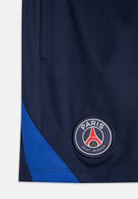 Shorts sportivi blu navy con finitura testurizzata, dotati di un pannello laterale blu e di un logo circolare con "PARIS SAINT-GERMAIN" sull'orlo.