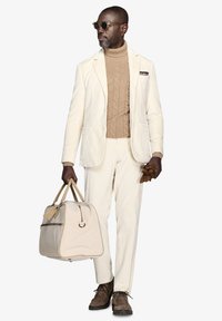 Beige cord-buksedragt med jakke og bukser, parret med en tan kabelstrik turtleneck. Brune ruskindssko og en beige taske. Guld solbriller.