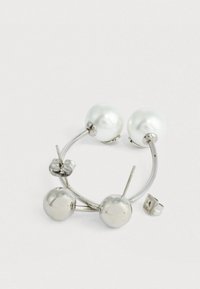 Un paio di orecchini a cerchio in argento con una pallina metallica rotonda a un'estremità e una grande perla bianca dall'altra, mostrati con i retro degli orecchini.