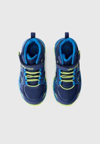 Des chaussures de sport pour enfants en bleu marine avec des accents verts. Elles sont fabriquées en matériaux en maille et synthétiques, avec une sangle ajustable et des semelles texturées.