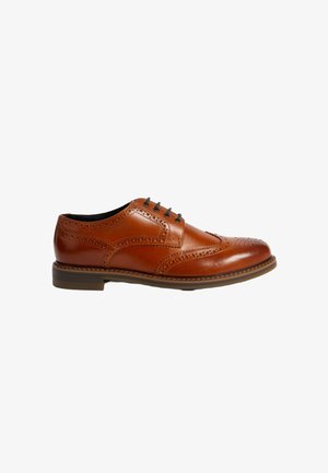 Chaussure habillée en cuir tan avec un design à bouts fleuris, perforations décoratives, bout rond et semelle contrastante. Dispose de cinq oeillets pour les lacets.