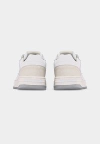 Ζευγάρι λευκά αθλητικά παπούτσια με μπεζ γούνα στη φτέρνα, γκρι σόλες και το λογότυπο "just cavalli" τυπωμένο στη μεσαία σόλα, σε προβολή από πίσω.