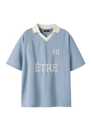 Camisa de manga corta de color azul claro con cuello blanco, escote en V, número 10 en el pecho y la palabra "ÊTRE" impresa debajo del número.