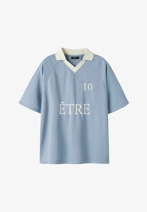 Chemise bleu clair à manches courtes avec col blanc, col en V, numéro 10 sur la poitrine et le mot « ÊTRE » imprimé sous le numéro.