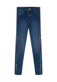 Blå denimjeans med flerfärgad "Guess" brodering som löper vertikalt längs ytterkanterna på båda benen.