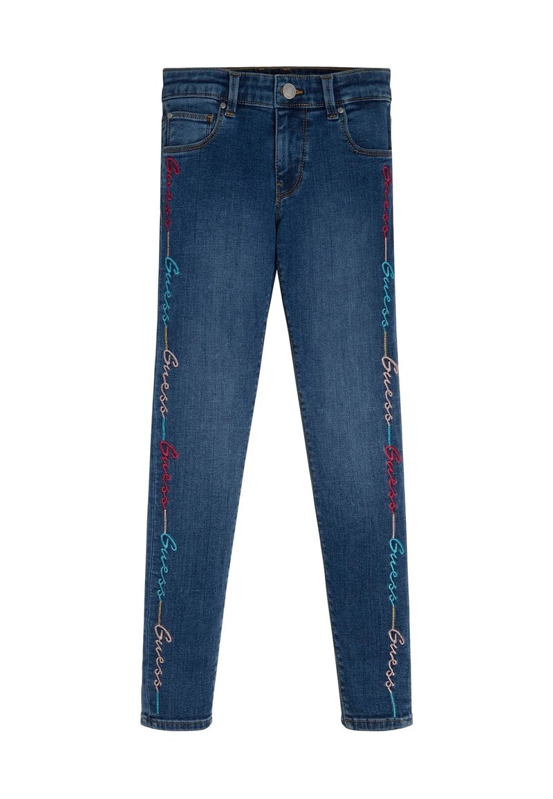 Blå denimjeans med flerfärgad "Guess" brodering som löper vertikalt längs ytterkanterna på båda benen.