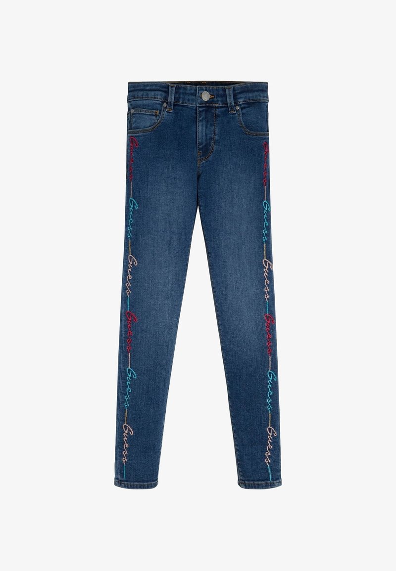 Modré džíny z denimu s barevným vyšíváním "Guess", které probíhá svisle podél vnějších švů obou nohavic.