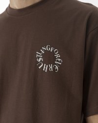 Braunes Baumwoll-T-Shirt mit Rundhalsausschnitt. Es hat eine kreisförmige Grafik mit dem Text "HUSTLING FOR EVERY CENT" in kontrastierenden Farben.