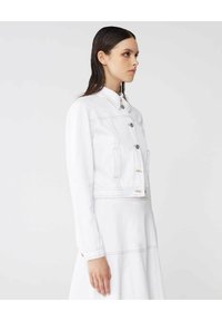 Giacca di jeans bianca con colletto, maniche lunghe, bottoni frontali e due tasche sul petto. Presenta cuciture visibili e un design accorciato.