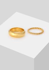 To guld ringe: en glat, bred band og en snoet, tynd band, begge med blanke overflader. Vist på en lys grå baggrund.