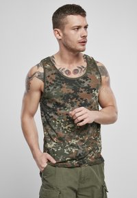 Kamerát mintázó, kerek nyakú pamut ujjatlan felső, zöld, barna és fekete színek keverékével. A modell keze a zsebében áll.