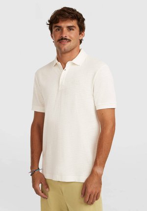 Polo de manga corta en color crema claro, confeccionado en tela texturizada. Cuenta con un cuello clásico y una tapeta con dos botones. Detalle sutil del logo.