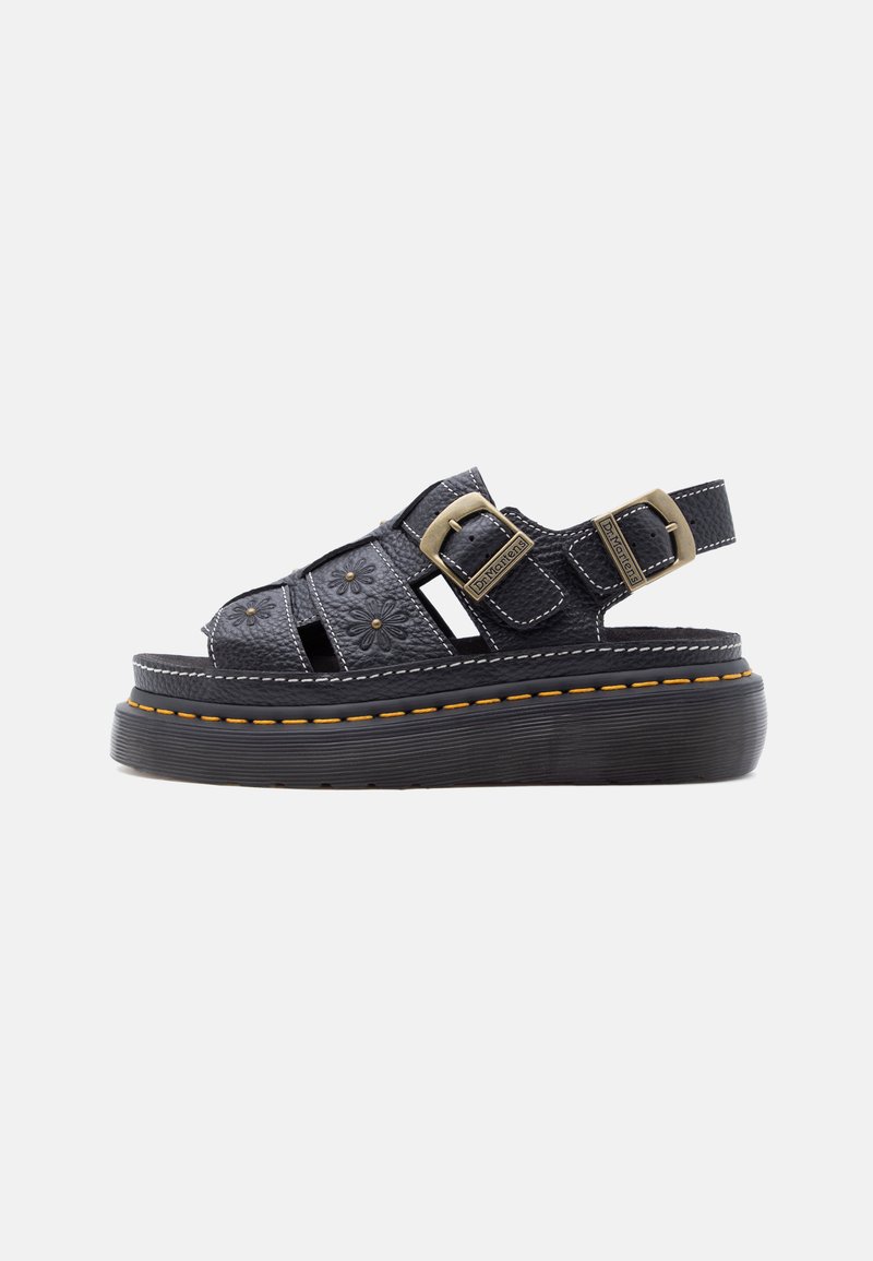 Μαύρο δερμάτινο σανδάλι πλατφόρμα με λουλουδάτες εγκοπές, διπλές ορειχάλκινες αγκράφες και κίτρινη ραφή σε παχιά λαστιχένια σόλα.