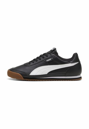 Baskets basses noires Puma avec bande latérale blanche, semelle en caoutchouc couleur gomme et lacets noirs, vues de profil droit sur fond blanc.