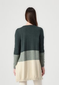 Larga chaqueta de punto multicolor que presenta rayas horizontales en verde oscuro, gris y crema. Textura suave y bolsillos laterales.
