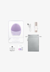 Dispositivo per la pulizia del viso in silicone viola, cavo di ricarica USB, siero, guida rapida e borsa grigia per il riporrio in confezione trasparente.