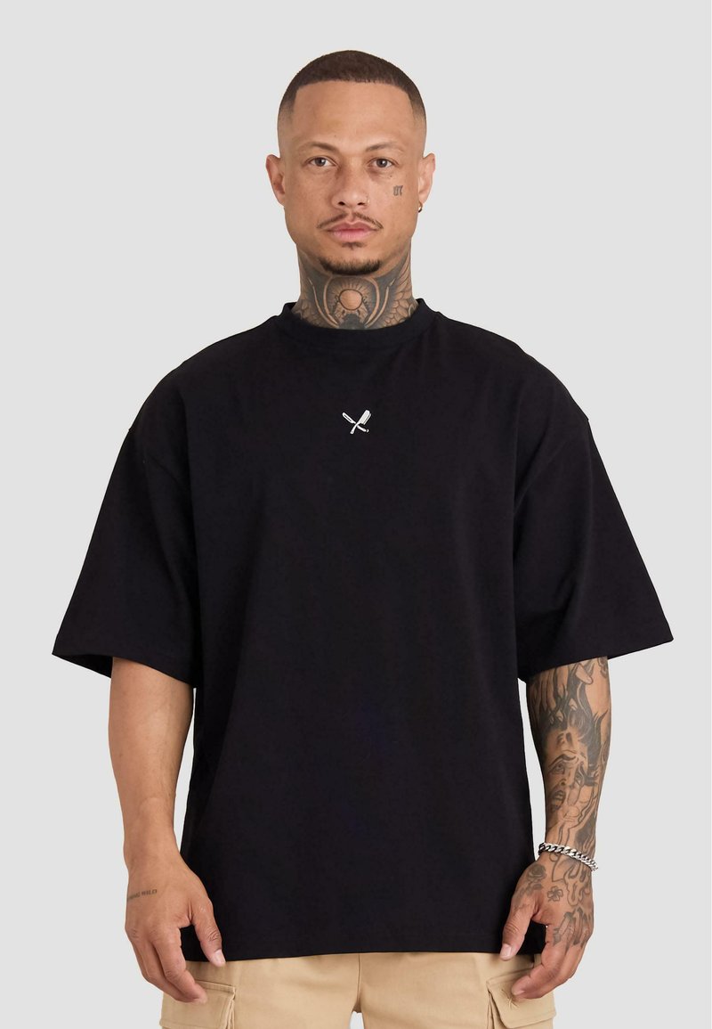 Czarny bawełniany t-shirt z krótkimi rękawami, w luźnym kroju, z małym białym logo na klatce piersiowej. Gładka faktura i okrągły dekolt.