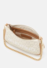 Valentino-väska i beige tyg med logomönster, guldkedjesnor, dragkedjestängning och en innerficka med en brun läderetikett.